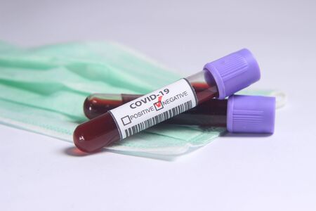 Close Up Photo, Simple Conceptual, Glass Blood Covid-19 Test tube above N95 Surgical Mask
