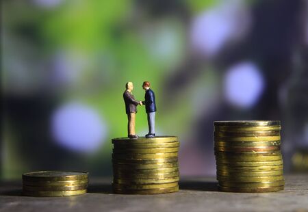 Simple Illustration Photo Successfull Bussiness Transaction, Two Man Handshaking at golden indonesia 500 Rupiah Coin, Green Forest as a backgroundの写真素材