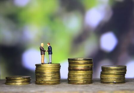 Simple Illustration Photo Successfull Bussiness Transaction, Two Man Handshaking at golden indonesia 500 Rupiah Coin, Green Forest as a backgroundの写真素材