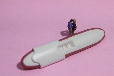 illustation photo for Lovely moment, Young Couple Mini figure Toy kissing beyond Pregnancy test pack...