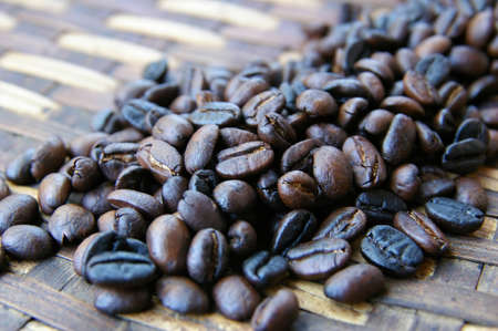 Dark brown coffee beans on a ratan trayの写真素材