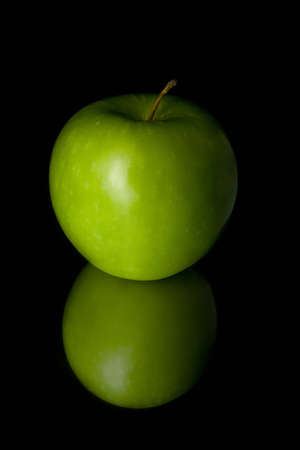 Shiny green apple isolated on the shiny black backgroundの写真素材