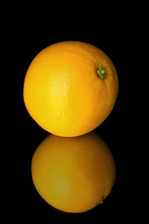Shiny ripe orange isolated on the black backgroundの写真素材