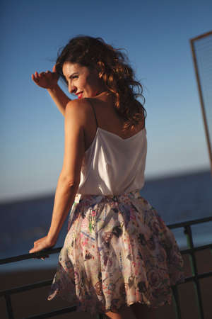 beautiful young woman in flowered dress sitting among dense vegetationの写真素材