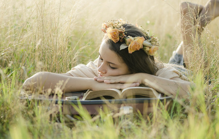 A young girl sleeping with her head on a bookの写真素材