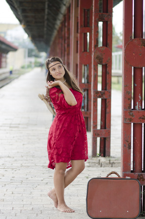 barefoot girl with suitcase waiting at the train stationの写真素材