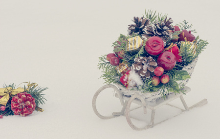Wooden toy sledge with Christmas decoration on snowy backgroundの写真素材