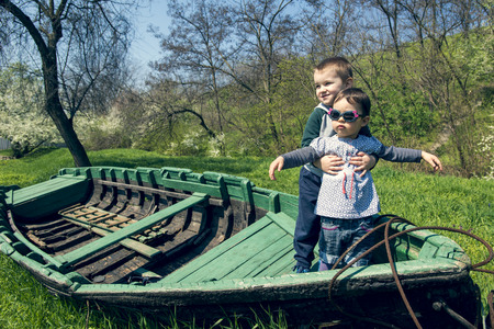 Little girl with brother having fun in an old boatの写真素材