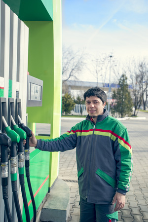 Smiling worker at the gas station, while filling a carの写真素材