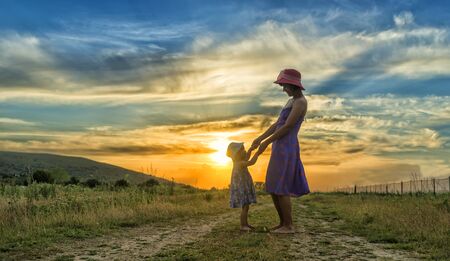 happy mother and daughter having fun at sunsetの写真素材
