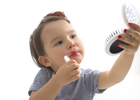 Fashion little girl applying lipstickの写真素材
