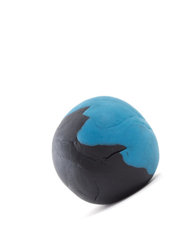 rolling blue and black  plasticine ball on white backgroundの写真素材