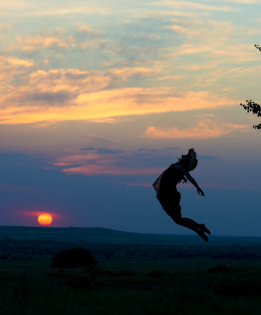 silhouette of a beautiful girl jumping in the sunsetの写真素材
