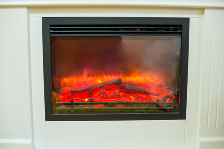White luxury artificial electronic fireplace with firewoods isolated on whiteの写真素材