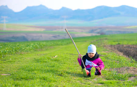 little girl sitting in the green fieldの写真素材