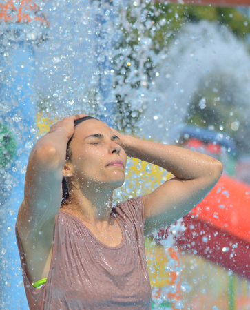 Beautiful woman enjoying under a water jet with thousands of drops in the backgroundの写真素材