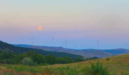 Wind station turbines and full moon at the skyの写真素材
