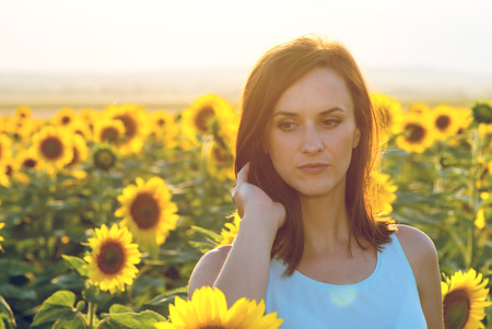 Woman in sunflower field at sunsetの写真素材