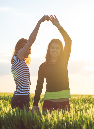 two young girls having fun in the wheat field in sunsetの写真素材