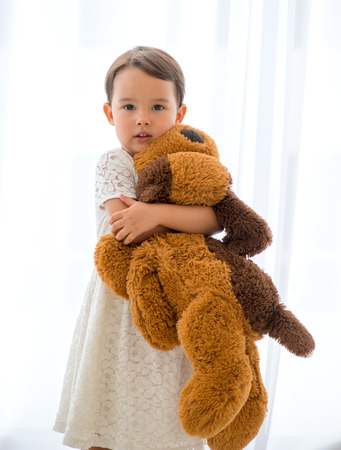 Cute little happy girl hugging big brown teddy bearの写真素材