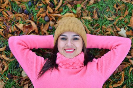 woman lying on autumn leaves, outdoor portraitの写真素材