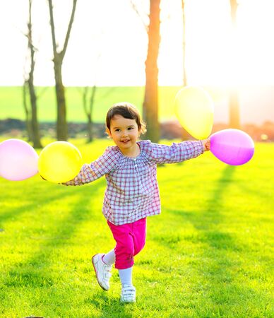 Little girl with balloons outdoors, dancing and enjoying natureの写真素材