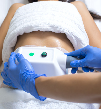 young woman getting cryolipolyse treatment in cosmetic cabinetの写真素材