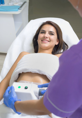 Pretty young woman getting cryolipolyse treatment in cosmetic cabinetの写真素材