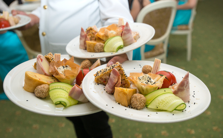 Waiter carrying plates with appetizers on some festive eventの写真素材