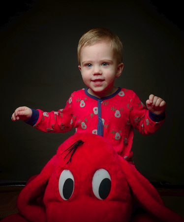 cute blonde little boy in red with his toyの写真素材