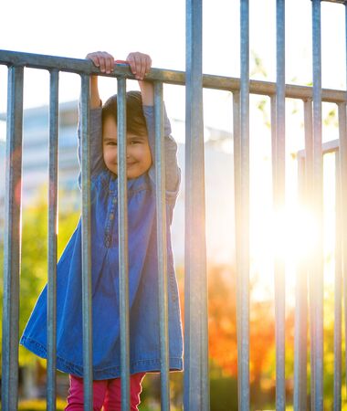 Little girl play on playground with white blur park background at sunsetの写真素材