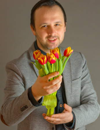 Smiling man offering a bunch of fresh flowersの写真素材