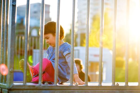 Little girl play on playground with white blur park background at sunsetの写真素材