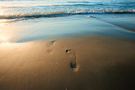 Beach wave and footprints at sunset timeの写真素材