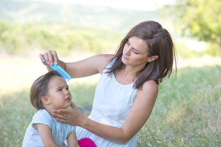 Young mother arranging her daughter's hairの写真素材