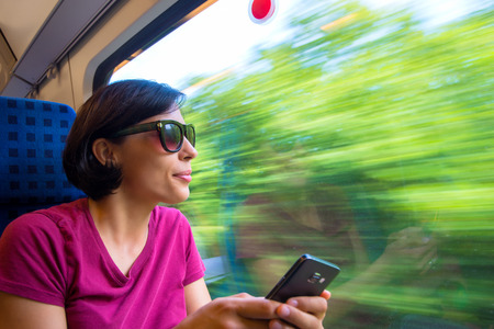 Woman texting on her phone during her trip in trainの写真素材
