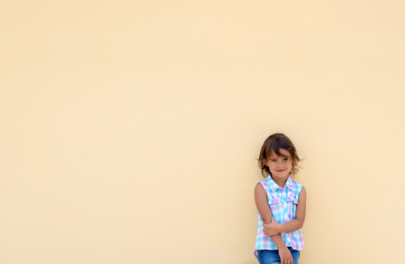 Little girl smiling and possing next to a yellow wallの写真素材