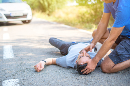 Man giving first aid in car accidentの写真素材