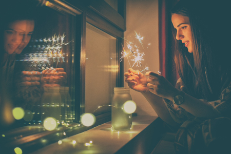 young woman who lights fireworks at homeの写真素材