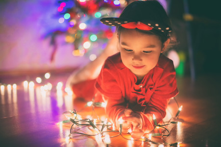 Little girl with Christmas lightsの写真素材