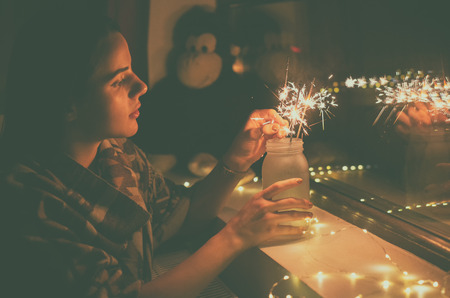 young woman who lights fireworks at homeの写真素材