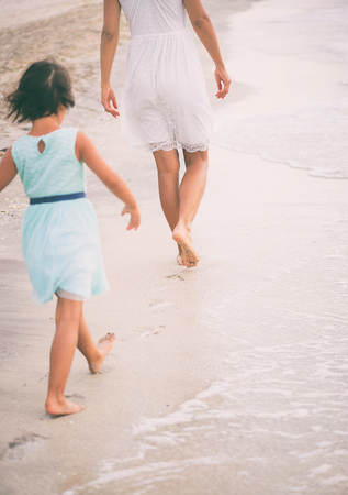 The little girl is trying to walk in the footsteps of her mother. Education conceptの写真素材