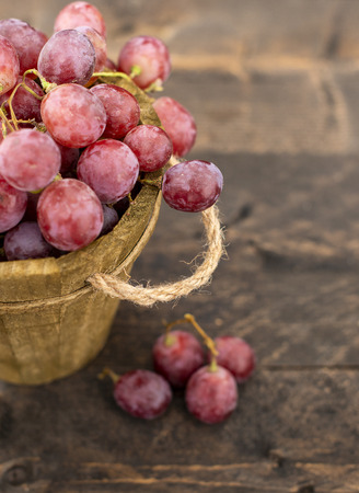 Rose grapes in wooden bucket on a woden tableの写真素材