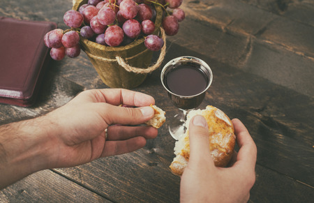 Man breaking the bread, with wine, grapes and Bible in the backgroundの写真素材