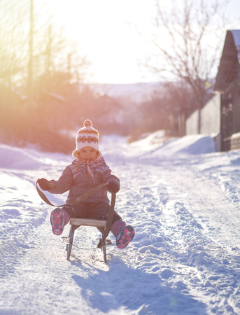 Little girl having fun with an old sleigh at countrysideの写真素材