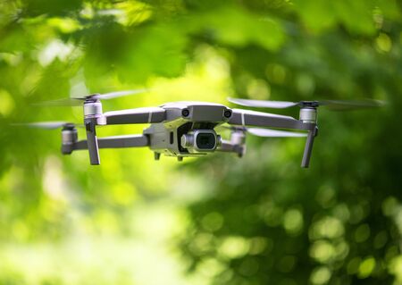 Flying drone with camera hovering inside a forrest, natural backgroundの写真素材