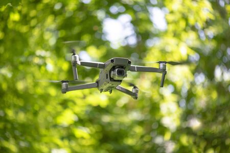 Flying drone with camera hovering inside a forrest, natural background