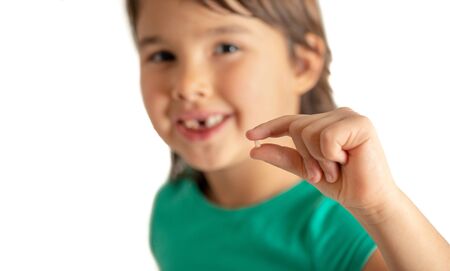 Girl with tooth in hands on isolated white background. Happy and proud