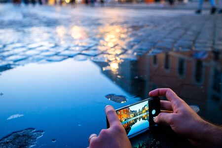 Man taking pictures of the cathedral of Saint Peter from the Vatican, reflected in the pondの写真素材