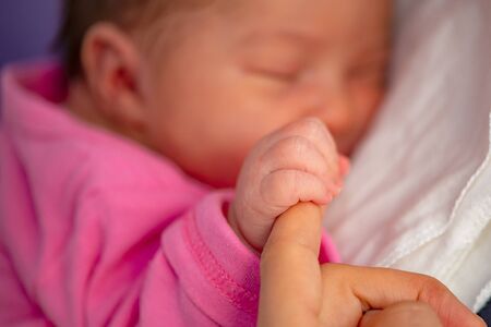 Newborn baby hold mother`s finger when he is layed on the bed.